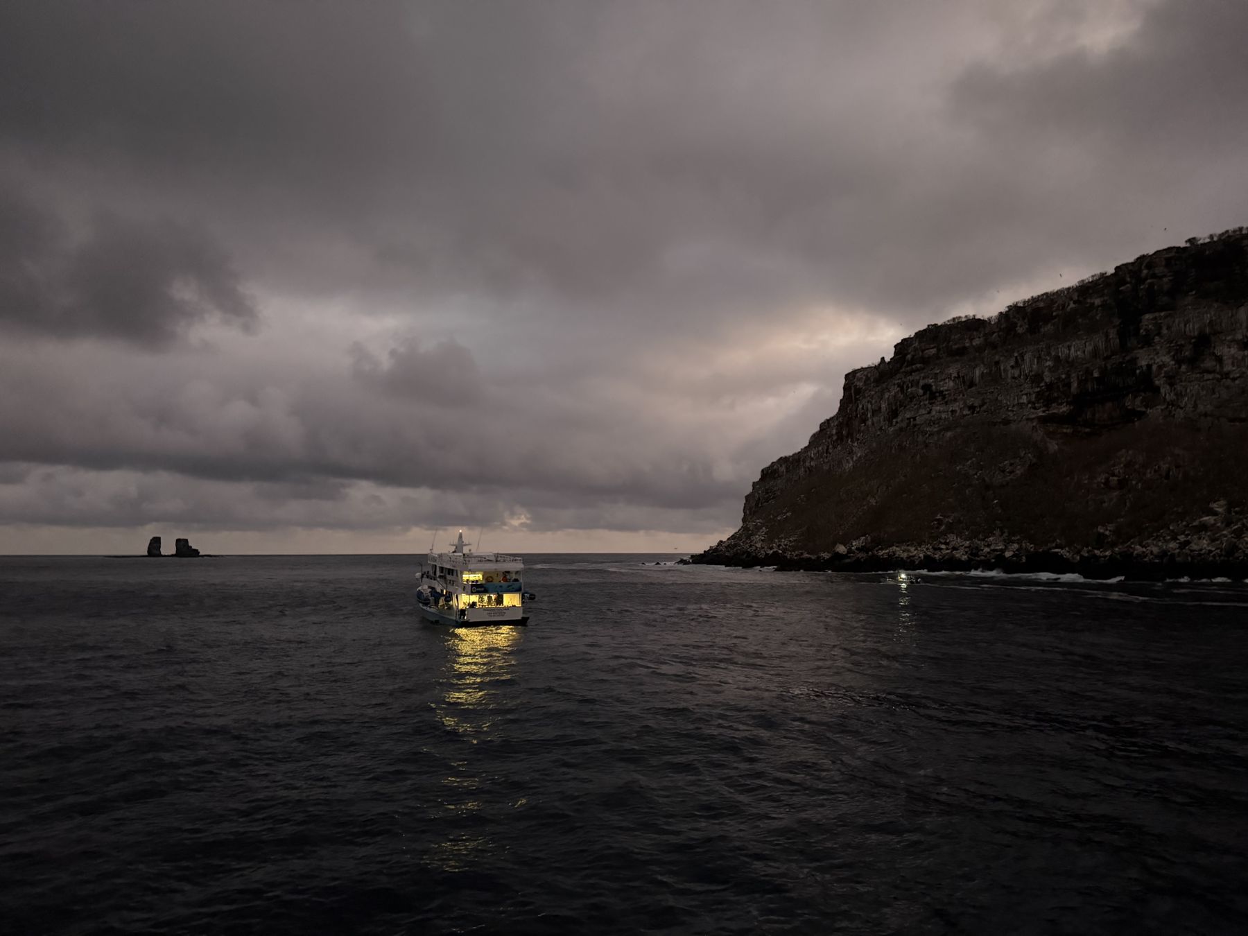 The liveaboard at anchor under a stormy dusk sky