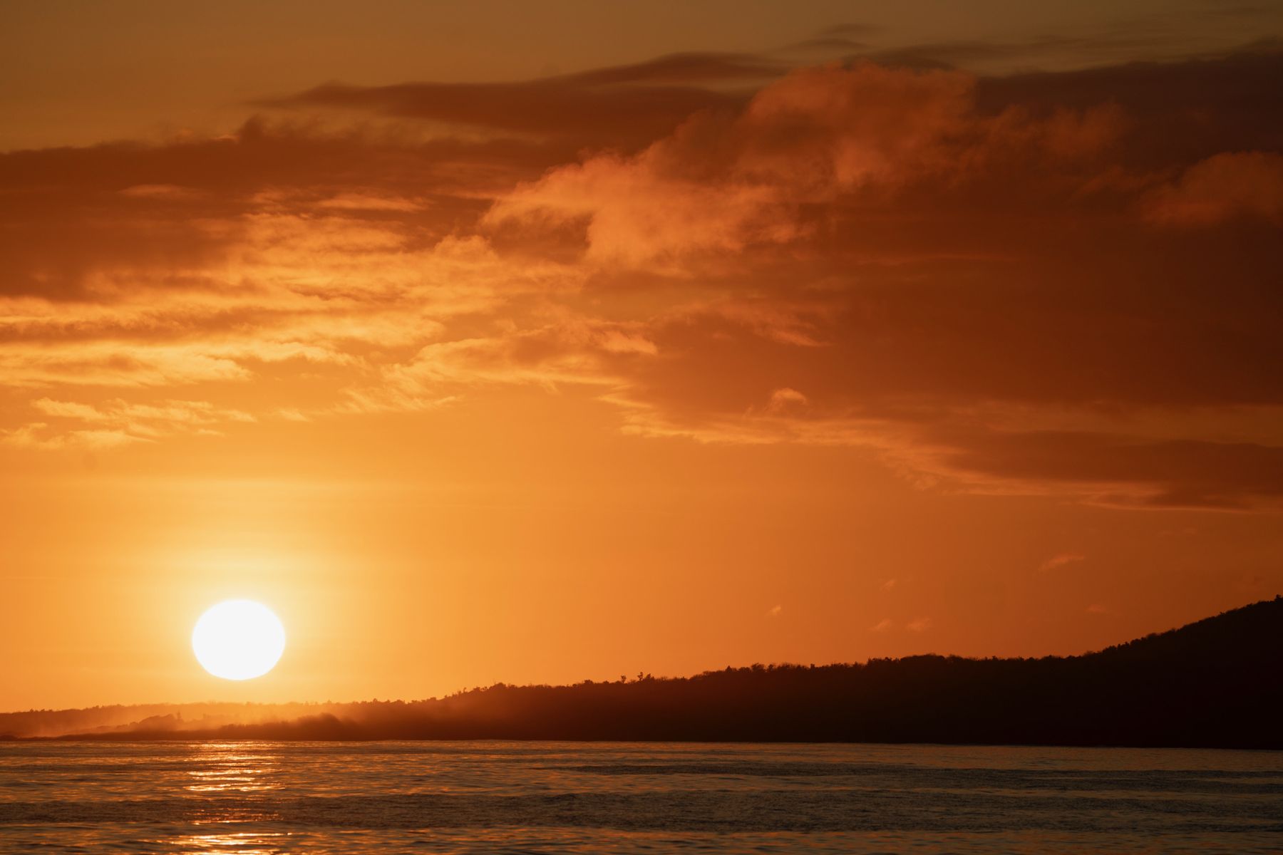 A deep orange sunset over an island silhouette