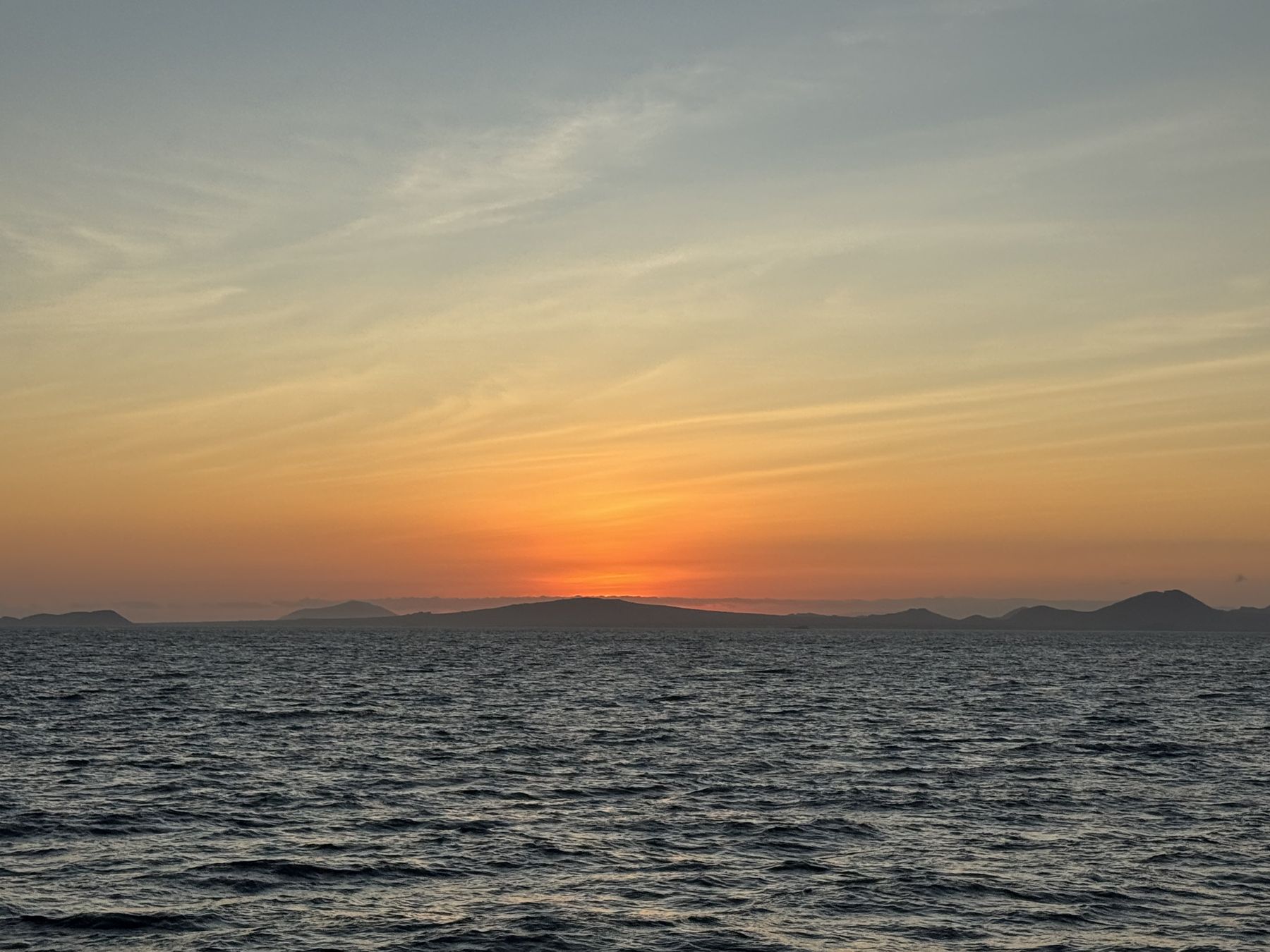 Sunset over open water and distant islands